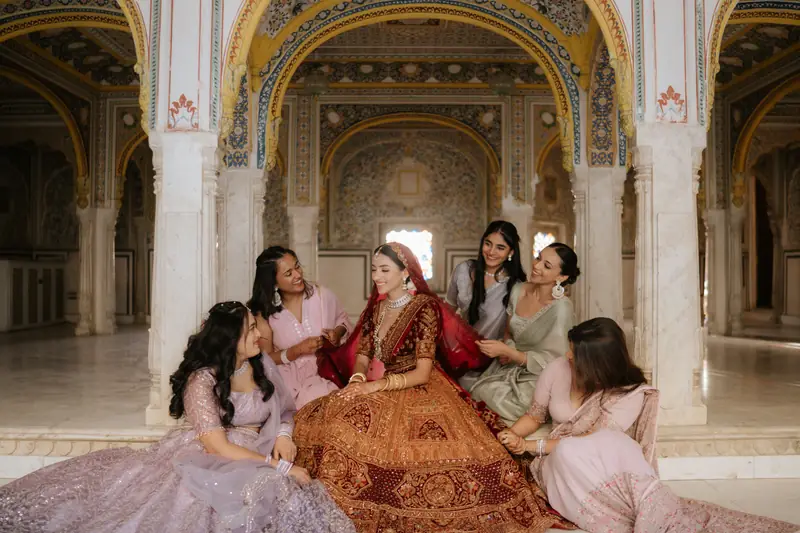 A bride laughing with her friends beneath the ornate arches of a heritage venue