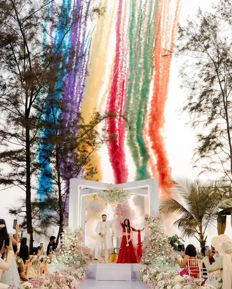 A couple celebrating beneath a floral mandap and colourful streamers at a Meragi wedding