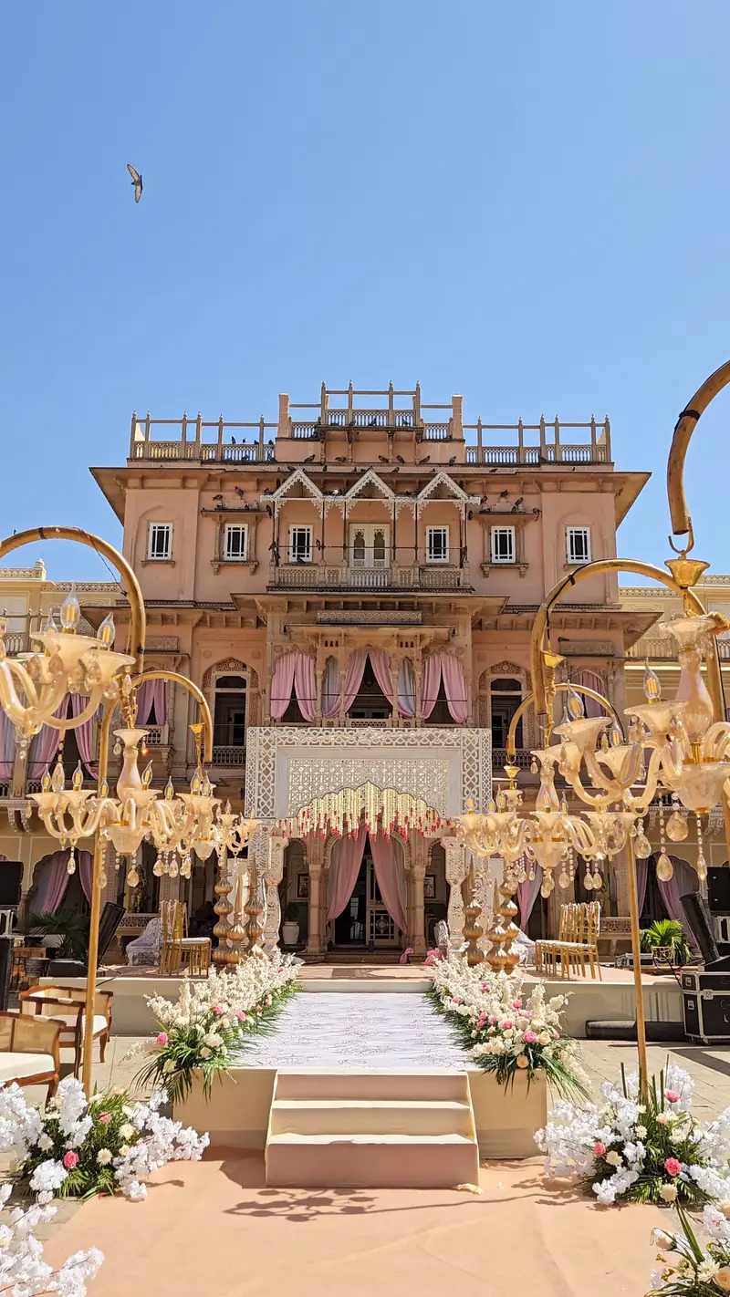 An elegant palace courtyard wedding setting with floral arrangements and hanging chandeliers