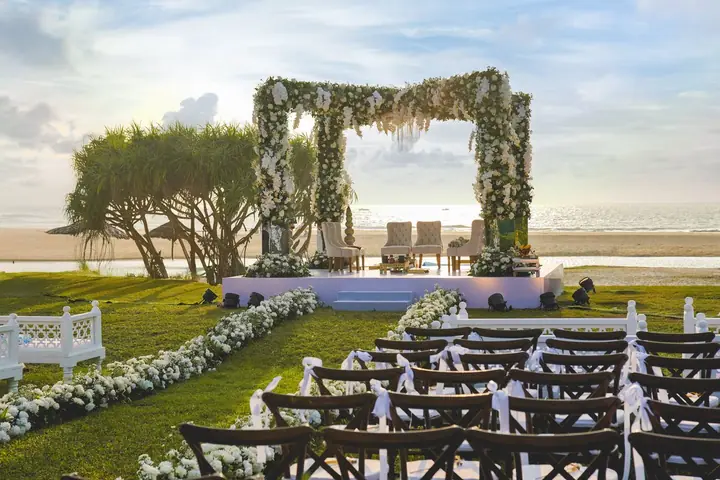 A white floral mandap beside the sea